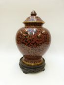 A large cloisonné ginger jar in red and black floral design, on hardwood stand, 39.
