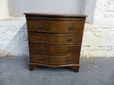 Small serpentine fronted chest of four drawers with brushing slide above,