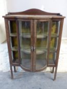 A late 19thC/early 20thC bow fronted corner cupboard with inlaid decoration,