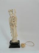 An early 20thC Chinese ivory figure of a Geisha and a small carved ivory puzzle ball