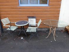 A garden table and two chairs together with another glass-topped table