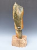 An African Shona green stone carving of a stylised head, signed P Heoleen, on a wooden plinth,