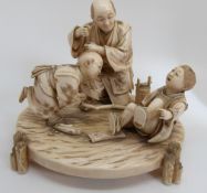 A late 19th / early 20thC Japanese ivory figural group depicting a father and two sons playing,