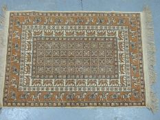 A Persian carpet with brown and cream decoration of deer, horses and riders,