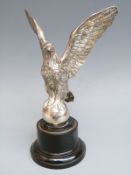 A car mascot formed as an eagle or similar bird mounted on a ball,