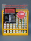 NGK spark plug wall-mounted retail dispenser with approximately 80 unused spark plugs