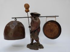 An oriental gong formed as a man holding a cane with bell to one end and gong to other,