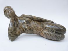 An African Shona stone carving of a reclining female figure, signed Artwell Nduna,