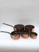 A graduated set of five copper saucepans,