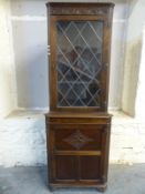 An oak double height corner cupboard with glazed top door,