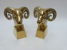 A pair of brass bookends in the form of ram's heads mounted on square plinths,