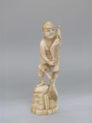 A signed Japanese Meiji period okimono of a man holding a fish with cormorant beside a rock,