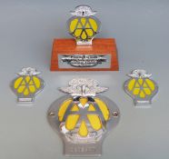 A Guernsey AA car badge and three 40 year anniversary small badges, one Jersey on base,