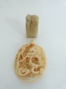 An early 20thC carved ivory pendant and a soapstone carved seal,