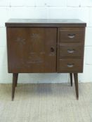A Chinese sewing cupboard with fold out table top and carved scenes raised on slender tapering legs