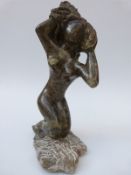 An African Shona flecked green and black stone carving of a kneeling female figure, signed A Nduna,