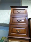 A narrow chest of three drawers,