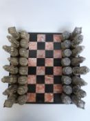 A stone chess set with figural pieces in the form of The Scots and Tudors, with marble board,