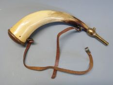 A horn powder flask with brass mounts and leather sling.