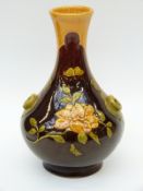 A Bretby style art pottery vase decorated with flowers and ring handles in relief on a brown ground,