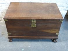 A hardwood travelling trunk raised on ball and claw feet with brass fittings W96 x D55.