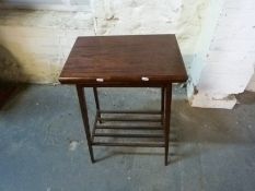 A fold over mahogany games table with rack below, width 50.