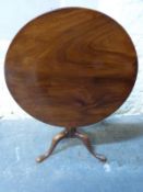 A circular pedestal tilt top table raised on tripod base,