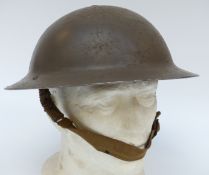 A WWII military helmet with lining and canvas chin strap,