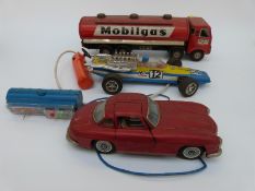 Three Japanese tinplate toys comprising a friction powdered Mobilgas tanker and two power steering