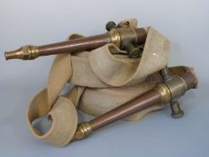 Two vintage canvas fire hoses with bronze/copper nozzles and fittings