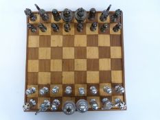 A steel chess set, each piece constructed from steel nuts and bolts, with wooden chess board,