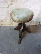 An adjustable piano stool with carved tripod base
