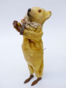 Clockwork tinplate bear playing a mandolin with golden fur and internal music box, 17cm tall.