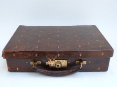 An Edwardian brown leather case with silk lining, embossed with gilt fleur de lys,