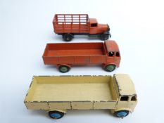 Three pre-war Dinky Toys diecast model lorries including two trucks and an animal wagon.