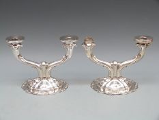 A pair of white metal candelabra with scrolling Rococo base leading to a two-branch stylised