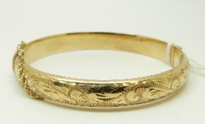 A 9ct gold bangle with engraved decoration, 10.