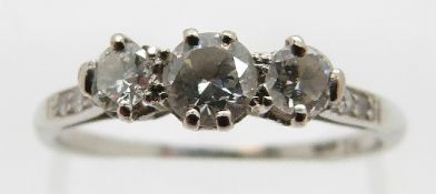 A platinum ring set with three round cut diamonds with further diamonds to the shoulders,