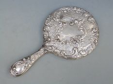 A hallmarked silver hand mirror with embossed decoration