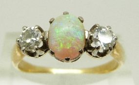A Victorian / Edwardian ring set with an oval opal cabochon and two old cut diamonds each