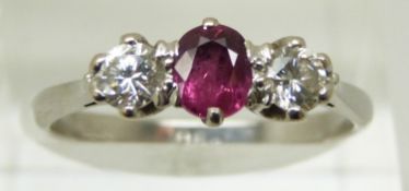 An 18ct white gold ring set with an oval cut ruby and two diamonds, each approximately 0.