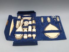 An Edwardian inlaid ivorine ladies dressing table / manicure set in folding damask case,