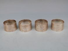 Four Art Deco hallmarked silver napkin rings with engine turned decoration,
