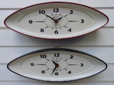 Two Newgate Bullitt wall clocks in elliptical shaped cased, one red the other black,