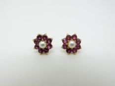 A pair of 18ct gold earrings set with a pearl surrounded by rubies