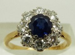 An 18ct gold ring set with a sapphire surrounded by diamonds totalling approximately 0.8ct, size M.
