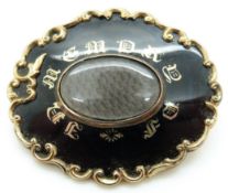 A Victorian mourning brooch set with black enamel with gold writing 