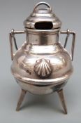 A novelty white metal lidded cauldron with swing handle, raised on three legs,