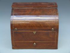 A Georgian inlaid mahogany six bottle tantalus in the form of a roll top bureau,
