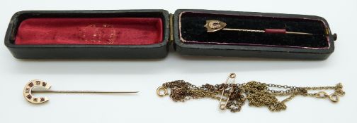 A yellow metal stick pin in the form of a horseshoe set with diamonds and rubies,